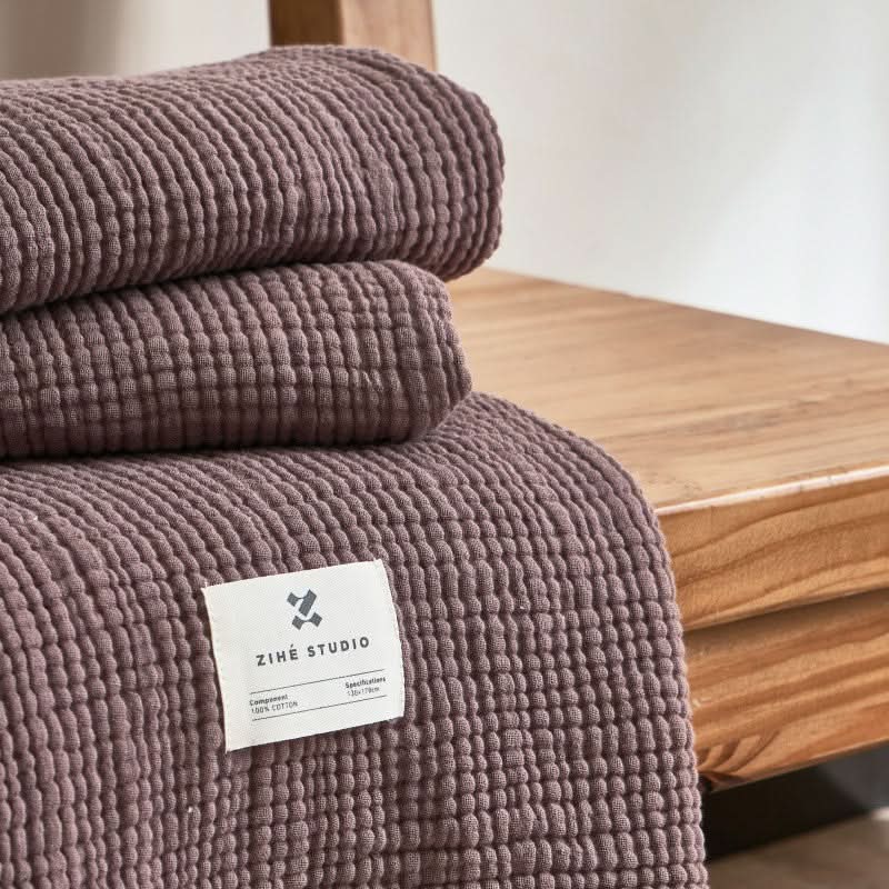 Cozy Textured Cotton Throw Blanket in mauve on a wooden surface.
